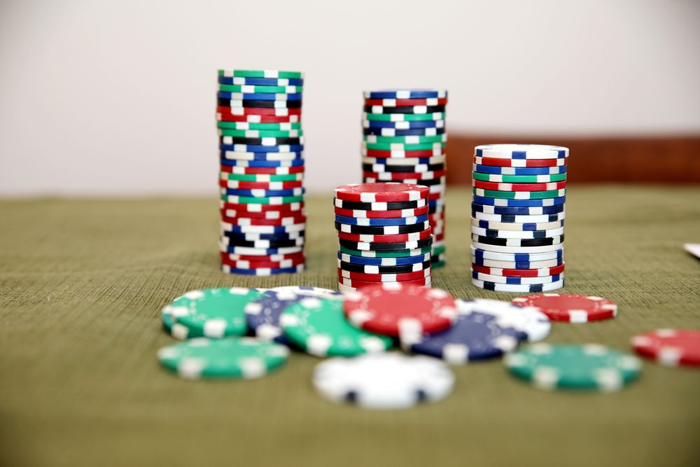 Chip poker berwarna-warni tersusun di atas kain hijau